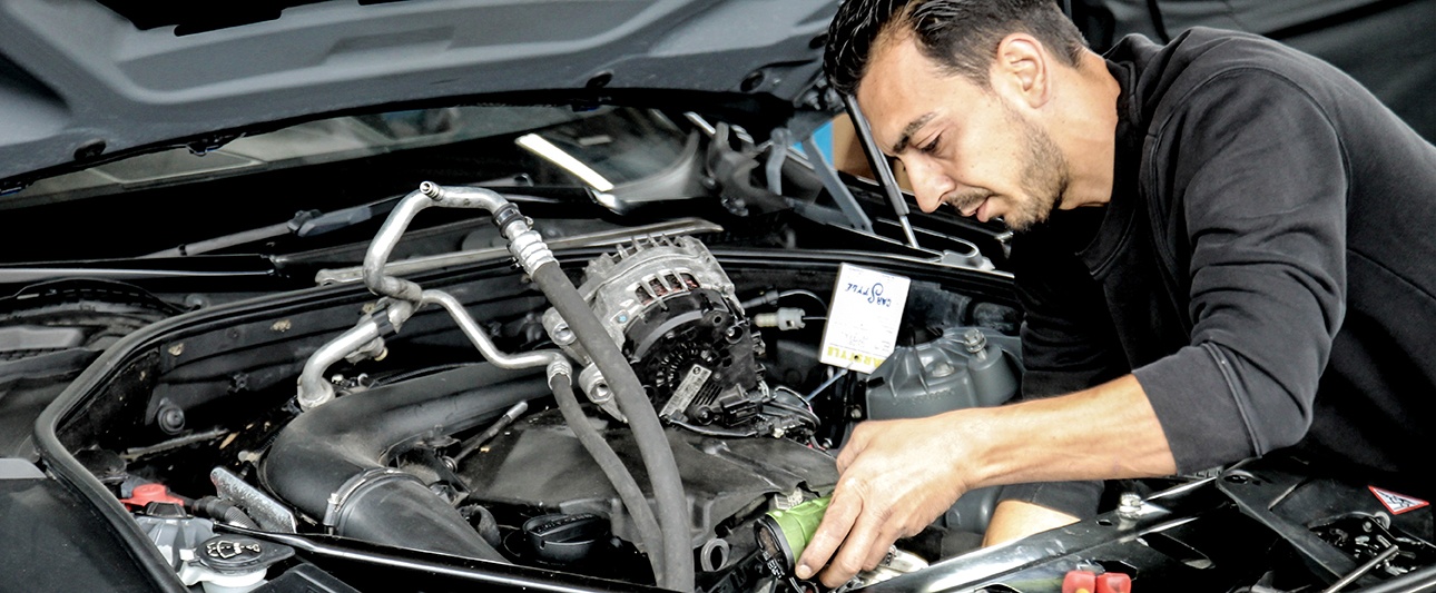 ein Monteur arbeitet am Motor eines Autos
