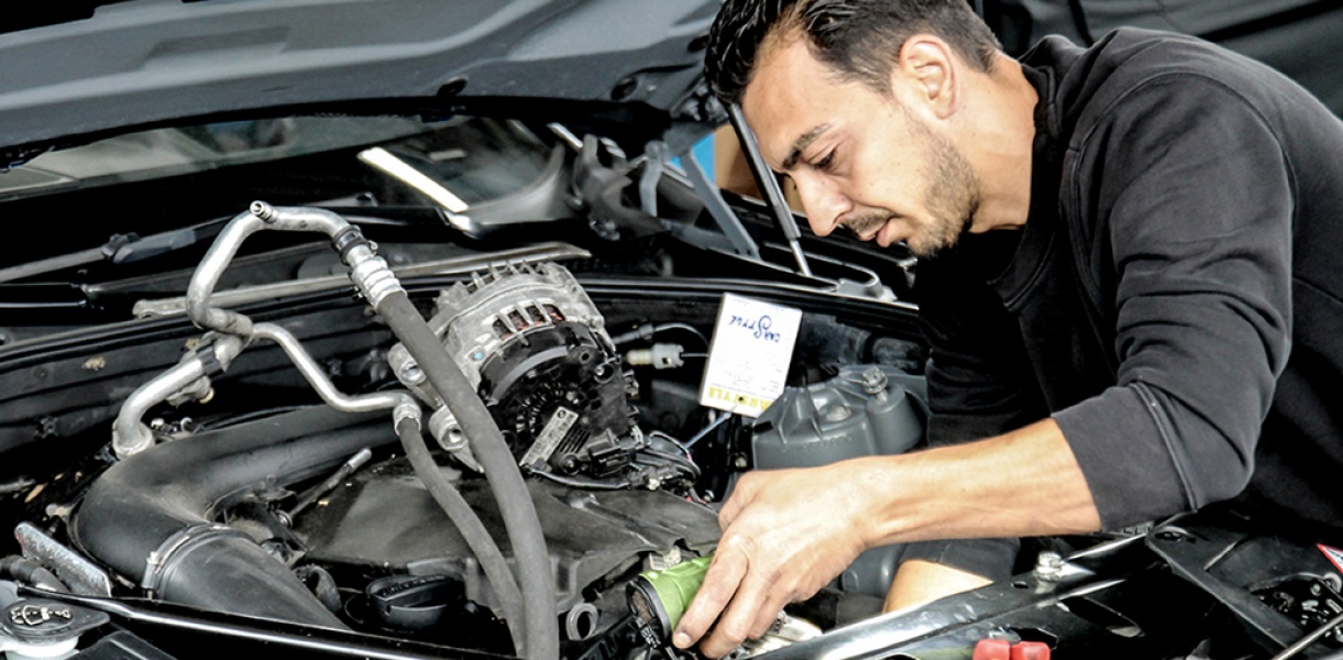 ein Monteur arbeitet am Motor eines Autos