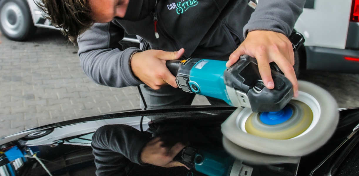 ein Mitarbeiter poliert ein Fahrzeug mit der Poliermaschine
